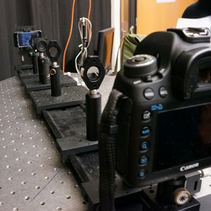 Pesquisadores usam uma câmera e lentes para simular um olho com miopia olhando para um "E" mostrado em uma tela iPod Touch modificado