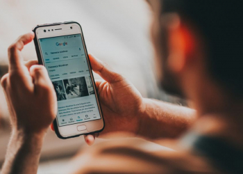 Homem segurando celular com página do google aberta