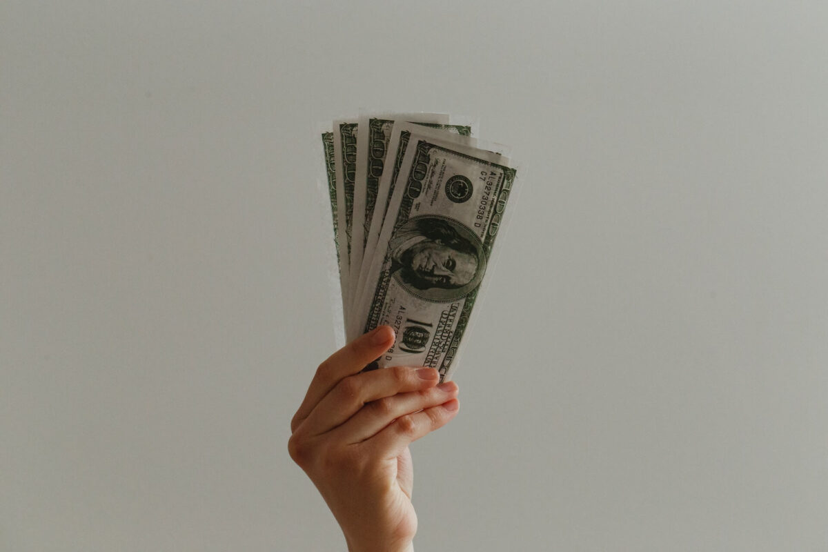 Imagem de uma mão segurando notas de dólar