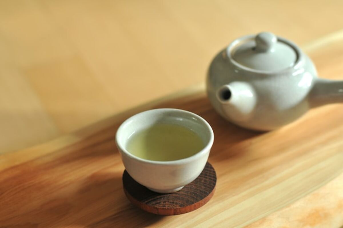 Imagem de um bule e uma xícara de chá verde