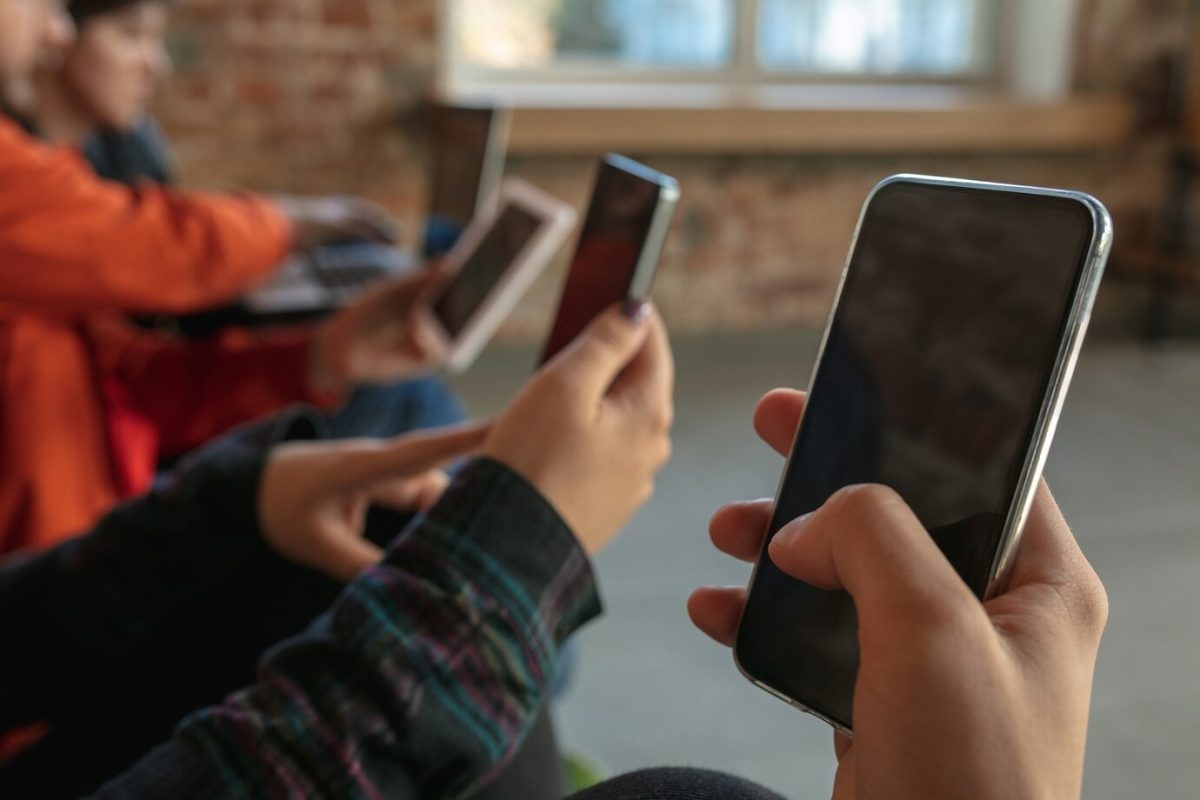grupo de jovens felizes sentados juntos em um sofa compartilhando noticias fotos ou videos de smartphones lendo artigos ou jogando e se divertindo redes sociais tecnologias modernas 155003 25447 TecheNet Smartphones brasil