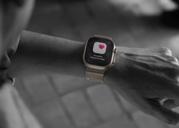 Uma pessoa olha para o seu apple watch, que exibe no ecrã uma notificação de saúde com o texto: 'possível hipertensão'.