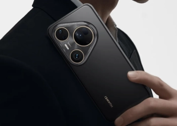 A traseira de um smartphone huawei pura em preto mate, seguro por uma pessoa de fato, destacando o seu grande módulo de câmara com três lentes.