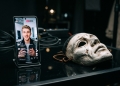 Telemóvel exibe retrato falso ao lado de máscara teatral para ilustrar a falta de transparência do selo criador de ia na rede social da meta.