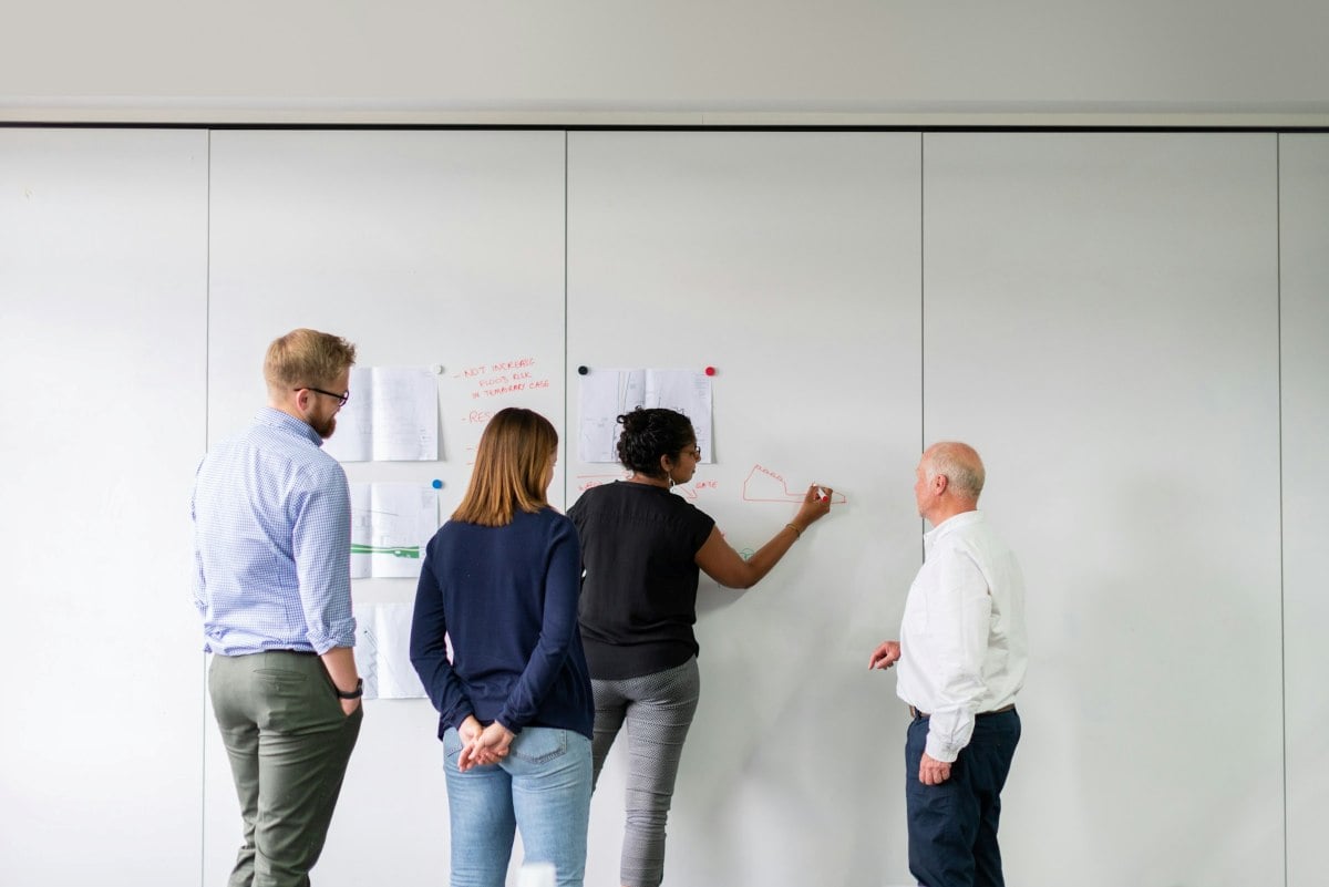 thisisengineering p5wrlynJR4A unsplash TecheNet Pessoas reunidas em uma sala de reunião enquanto uma delas escreve ideias em um quadro branco durante uma sessão de planejamento colaborativo.